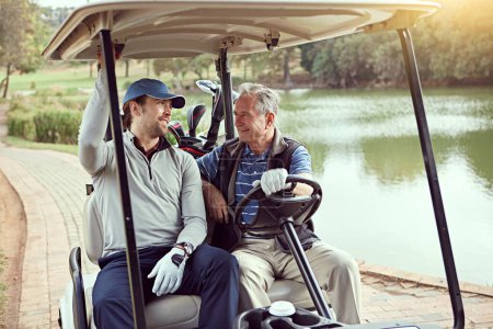 准备好玩游戏了一个老年人和他的成年儿子坐在高尔夫球场上的推车上